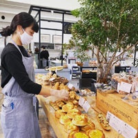ワールドベーカリー運営「パン・オ・ルヴァン」（熊本）店内でパンを並べる女性スタッフ